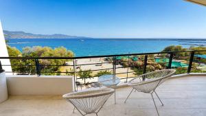 a balcony with two chairs and a view of the ocean at Seafront Luxury Apartment in Kalamata