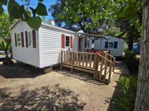 a tiny house with a porch and a deck at Vias Plage - Camping Les Salisses - Mobilhome in Vias