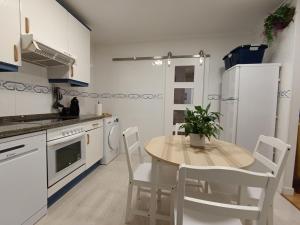 a kitchen with a wooden table and white appliances at El Llambrion in Posada de Llanes