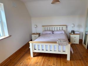 a bedroom with a white bed and two night stands at Golf central in Rosslare Harbour +5 photos