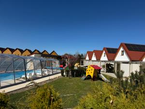 a backyard with a pool and a playground at KORALIA Domki Standard z basenem in Sarbinowo