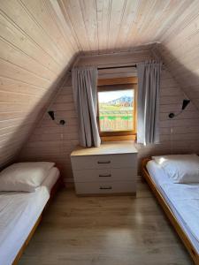 two beds in a small room with a window at KORALIA Domki Standard z basenem in Sarbinowo +9 photos