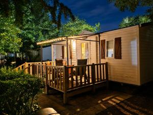 a tiny house with a porch and a deck at Vias Plage - Camping Les Salisses - Mobilhome in Vias