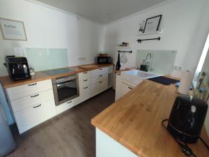 a kitchen with white cabinets and a wooden counter top at Ferienhaus Quell in Sankt Martin +16 photos
