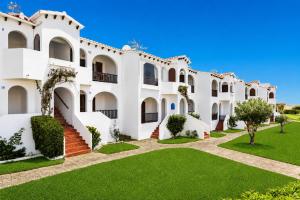 a large white building with a green lawn at Turquoise Menorca By the Sea in Son Bou
