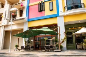 a patio with chairs and an umbrella in front of a building at Khách Sạn Cát House in Ha Long