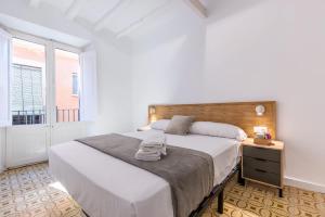 a white bedroom with a large bed and a window at Cavallers Suites - Unik Vacation in Tarragona