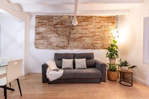a living room with a couch and a brick wall at Cavallers Suites - Unik Vacation in Tarragona