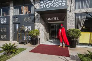 Ein Mann in einem roten Umhang steht vor einem Hotel in der Unterkunft Hôtel du Golf Mohammedia in Mohammedia