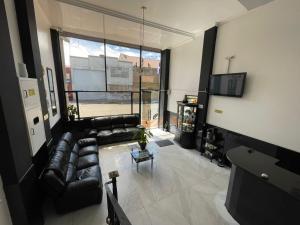 a living room with a leather couch and a large window at Hotel Ejecutivo 63 In in Bogotá