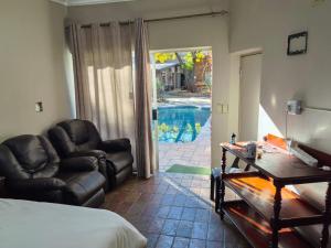 a bedroom with a bed and a couch and a table at Kameeldoring Guesthouse in Zeerust