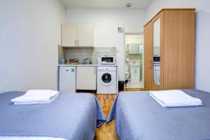 two beds in a small room with a kitchen at The Brompton Residence Hotel in London