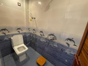 a bathroom with a toilet and dolphins painted on the wall at Govind atithi greh in Ayodhya