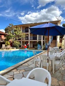 a pool with chairs and an umbrella next to a building at Estalagem do Carmo in Pirenópolis