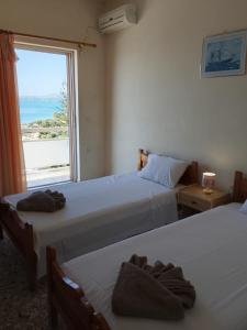 two beds in a room with a large window at EMILIOS SEE VIEW in Barbati
