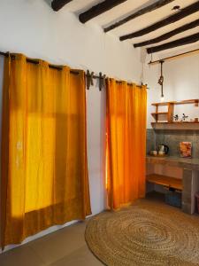a room with orange curtains and a rug at FURAHA GARDEN Rooms in Kendwa +24 photos