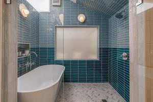 a blue tiled bathroom with a tub and a window at Crows Nest Condo 3BR Downtown in Anchorage