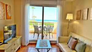 a living room with a couch and a tv and a balcony at CASAS DEL MAR - Oliva Nova - Primera línea de Playa in Oliva
