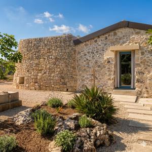 a stone house with a window and a stone wall at Masseria Petra in Martano