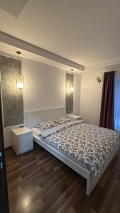 a bedroom with a bed with a comforter at Green Deluxe Apartment Cosmopolis in Ştefăneştii de Jos