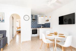 a kitchen and living room with a white table and chairs at Turquoise Menorca By the Sea in Son Bou