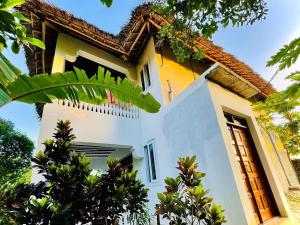 a yellow and white house with trees in front of it at Kome-Salsa Garden Comfortable big apartment in Jambiani