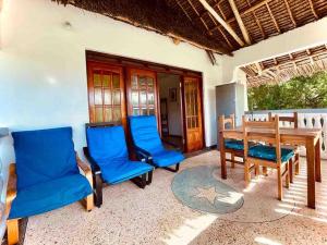 a patio with blue chairs and a wooden table at Kome-Salsa Garden Comfortable big apartment in Jambiani