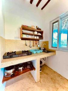 a kitchen with a counter with a stove and a sink at Kome-Salsa Garden Comfortable big apartment in Jambiani +24 photos
