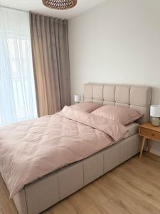 a white bedroom with a large bed and a chandelier at Moon&Mori in Augustów