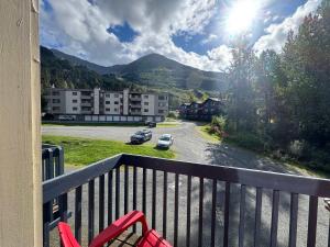 a red chair on a balcony with a view of a building at Alyeska Slope-Side Sanctuary in Girdwood