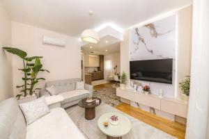 a living room with a white couch and a flat screen tv at Luxury Apartment Milos in Dobrota