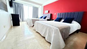 two beds in a room with a red wall at Hotel Victoria in Chinchiná