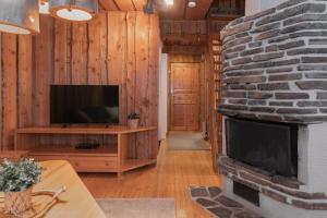 a living room with a stone fireplace and a television at Kelo Haven, 2 x skipasses Ruka-Pyhä included, skibus nearby in Ruka