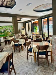a restaurant with tables and chairs and windows at Hotel Osumi in Çorovodë