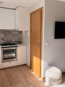 a kitchen with white cabinets and a door and a stool at Sunset holiday house in Liepāja