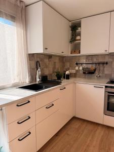 a kitchen with white cabinets and a sink at Sunset holiday house in Liepāja +8 photos