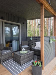a screened porch with wicker chairs and a table at Tähetee Majake in Palometsa +3 photos