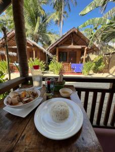 a wooden table with rice and a plate of food at Zhaya's Beachfront in El Nido