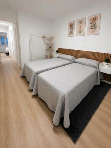 two beds in a white room with wooden floors at Casa Vilela in Arzúa