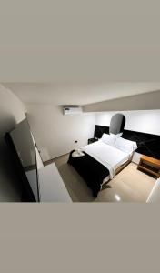 a white room with a bed and a tv at ARY Hotel in Valledupar