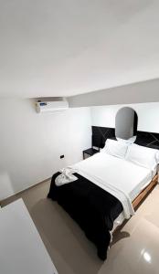 a bedroom with a large bed in a white room at ARY Hotel in Valledupar