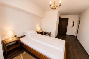 a bedroom with a white bed and two night stands at Pensiunea Alpin Marisel Self Check-in in Mărişel