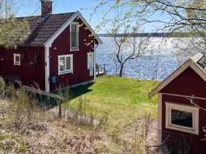 a red house on the shore of a body of water at 8 person holiday home in HJÄLTEVAD in Hjältevad