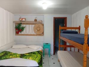 a room with two beds and a bunk bed at Pousada Boguitos - Pé na areia na Iha do Mel! in Paranaguá