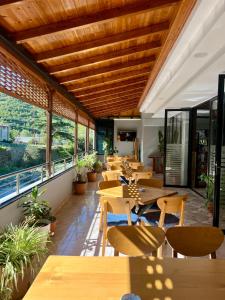 a restaurant with wooden tables and chairs and windows at Hotel Osumi in Çorovodë