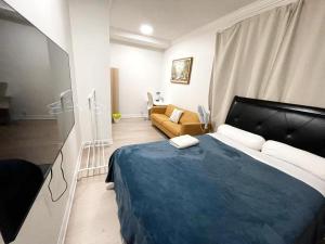 a bedroom with a blue bed and a couch at Queen Boutique Rooms in Toronto