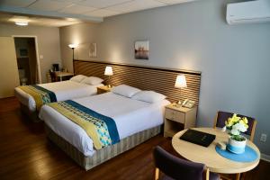 a hotel room with two beds and a table at Motel Bel-Eau in Montebello