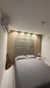 a bedroom with a large bed and a guitar at 1- Apartamento aconchegante 1200m do Centro in Serra Talhada