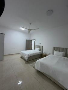a bedroom with two beds and a ceiling fan at جوهرة الخوض in Al Khawḑ
