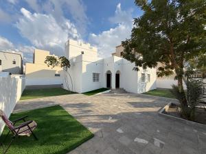 a white building with a chair in the yard at جوهرة الخوض in Al Khawḑ